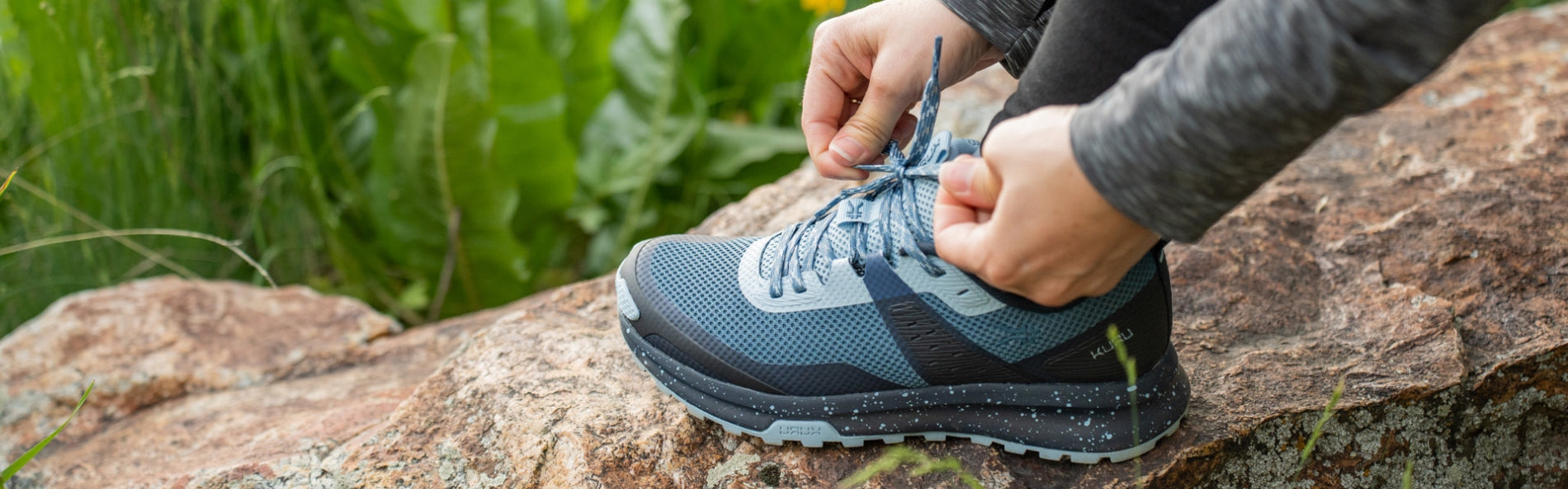 Woman tying KURU Footwear ATOM Trail Women's Sneaker in JetBlack-DarkTeal while hiking. perfect for heel pain. Providing Heel Pain Relief